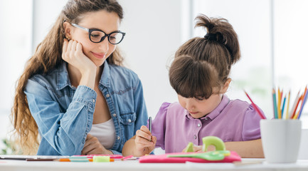 Teacher and girl drawing at school