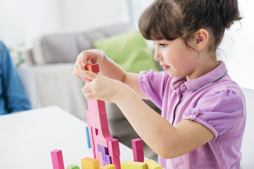 Cute girl playing with toy wood blocks