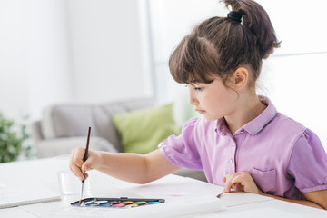 Cute preschool girl painting at home