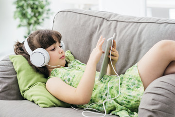 Cute girl relaxing on the sofa and using a tablet
