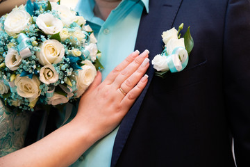 Wedding boutonniere on suit of groom and the hand of bride 