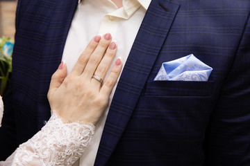 Wedding boutonniere on suit of groom and the hand of bride 