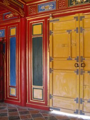 Bright yellow doors against a colourful red, blue and green wall with golden details