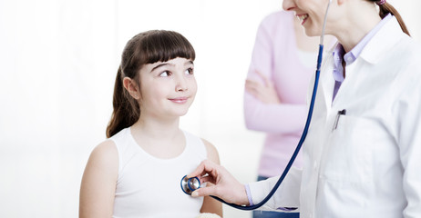 Doctor examining a cute smiling girl with a stethoscope