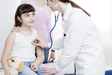 Doctor examining a cute smiling girl with a stethoscope