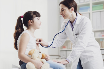Doctor examining a cute smiling girl with a stethoscope