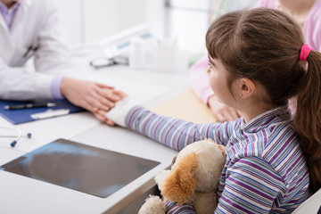 Pediatrician examining a young girl with an injured wrist