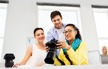 photography and creative people concept - photographers with camera at photo studio