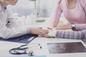 Pediatrician examining a young girl with an injured wrist