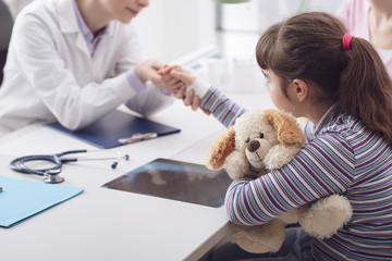 Pediatrician examining a young girl with an injured wrist