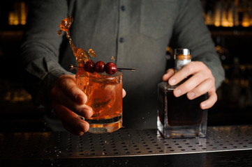 Bartender serving a cocktail glass decorated with a berries on the caretaker