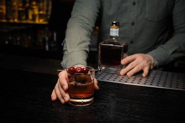 Bartender serving a cocktail decorated with a berries on the caretaker