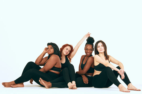 Four multiracial diverse woman in sportswear sitting on the floor and discussing the specificities of woman s training depending on type of figure