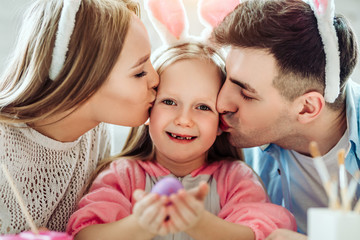 I love my parents very much for creating the atmosphere of the holiday. Happy little girl holding easter egg in hands.
