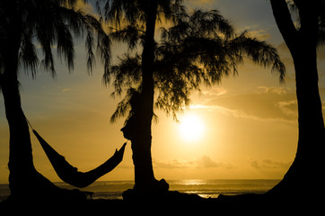 Mensch in Hängematte am Meer bei Sonnenuntergang im Urlaub