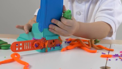 A two years old preschool child playing with modeling clay (compound). Smiling and looking at the camera. Early childhood education to children concept