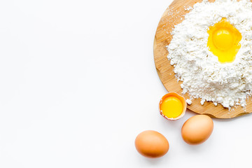 Making dough concept. Pile of flour and eggs on white background top view copy space