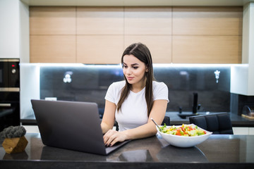 Young prety woman having healthy lunch while working on her notebook