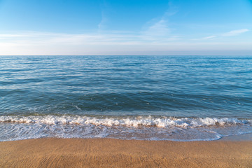 Empty beach with blue water and golden sand in sunny weather