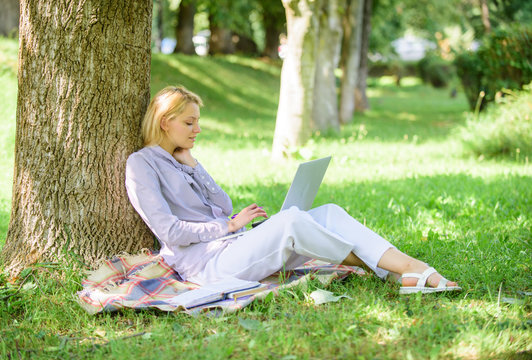 Work outdoors benefits. Woman with laptop computer work outdoors lean on tree trunk. Education technology and internet concept. Girl work with laptop in park sit on grass. Natural environment office