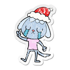 cute distressed sticker cartoon of a dog crying wearing santa hat