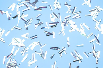 Silver confetti in the shape of rectangles on a blue background.