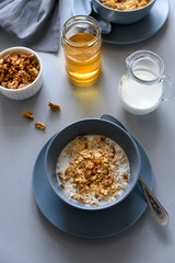 Granola bowl (oatmeal porridge) with blueberry, honey and milk on gray table. Flat lay. Selective focus. Healthy vegetarian food
