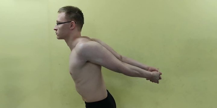 Sporty man stretching arm before gym workout. Fitness strong male athlete standing indoor warming up