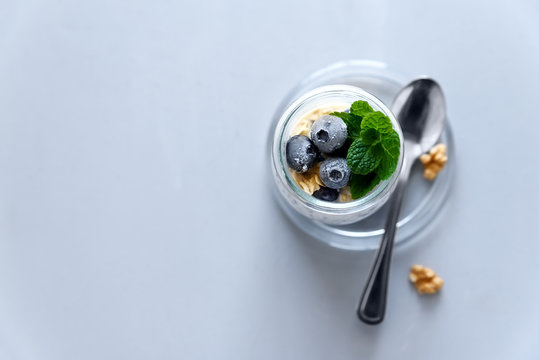 Chia Seed Pudding With Granola, Blueberry, Walnut And Honey Decorated Mint Leaves On Gray Background. Selective Focus. Healthy Eating Or Vegetarian Food Concept