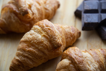 Fresh croissants with chocolate on wooden board