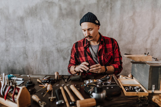 young man with moustache is involved in the gesign of jewelry. close up photo.