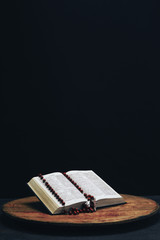 Bible and the crucifix beads on a old round table. Beautiful night background. Religion concept...