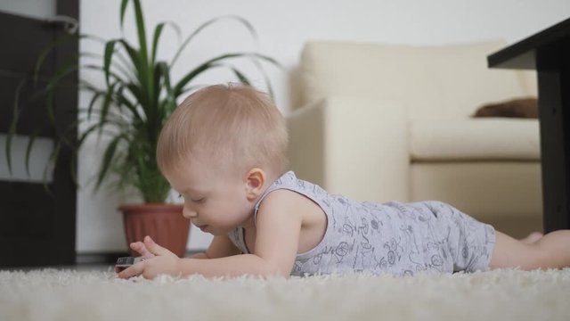 Little boy is watching cartoons on smartphone on the floor at home, lifestyle.