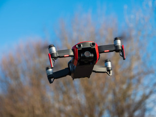 Kameradrohne im Flug vor unscharfem Hintergrund mit Baum