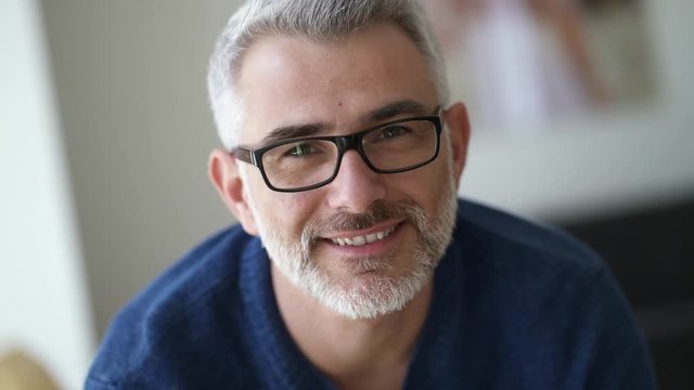 Mature man wearing glasses looking and smiling at camera