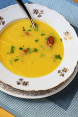 Yellow vegetable soup with roasted garlic pieces.