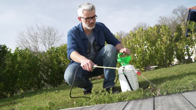 Man using garden sprayer on lawn in backyard