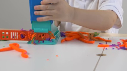 A two years old preschool child playing with modeling clay (compound). Smiling and looking at the camera. Early childhood education to children concept