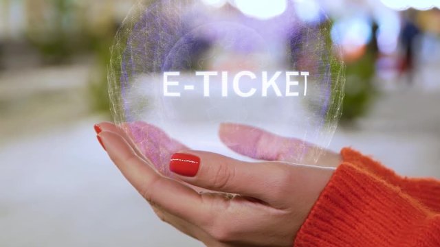 Female hands holding a conceptual hologram E-ticket. Woman with red nails and sweater with future holographic technology on a blurred background of the street
