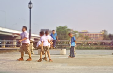 A group of children in a white school uniform and a blue sky running along the river.The school students play cheerfully along the river after school