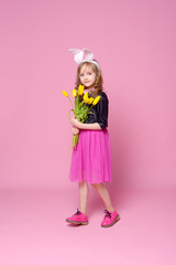 Funny girl in the shape of an Easter Bunny with a bouquet of yellow tulips. Concept of holidays, beauty and fashion. Selective focus.