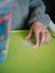 Three year old girl painting with colors on green table