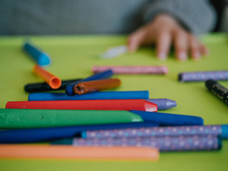 Three year old girl painting with colors on green table