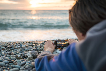 Back view close up young man filming video or taking photo pictures on his mobile cell phone during his adventure on sea shore Copy space.