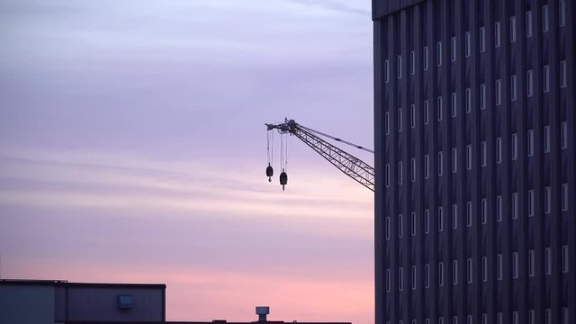 Construction crane with wrecking balls in the city during sunrise.
