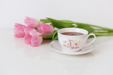 Fototapeta na wymiar Morning tea with pink tulips on white table. Close up. Soft focus. Spring concept. Happy Mother's Day, Women's Day or Birthday. Minimalism, copy space.