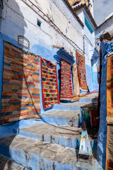 A vendor is selling some rugs in the streets of Chefchaouen, Morocco
