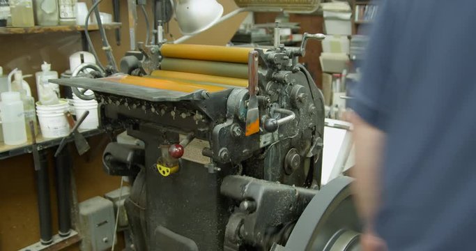 A Heidelberg platen letterpress printing press in operation ready to print with yellow ink.