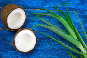 Fototapeta na wymiar top view coconut and aloe vera green leaves on a blue wooden table,natural cosmetics ingredients