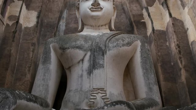 Pan down of the Wat Si Chum Buddha statue located in the Sukhothai Historical Park, Thailand.
